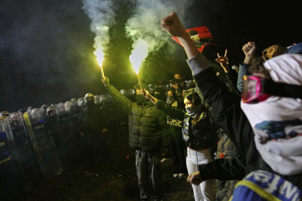 Людзі выкрыкваюць лозунгі побач з амапаўцамі падчас акцыі пратэсту пасля арышту і зняволення мэра Стамбула Экрэма Імамаглу, галоўнага суперніка цяперашняга прэзідэнта Турцыі Рэджэпа Эрдагана. 24 сакавіка 2025 года. Фота: Khalil Hamra / AP Photo / East News