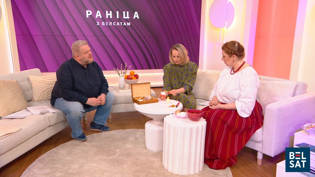 Усё гатова да распісвання яйка: схема, пісачок, воск, свечка, яйкі і міска з адварам. Анатоль Шырвель глядзіць, як Аліна Коўшык пачынае маляваць пад кіраўніцтвам Марыі Грыц. Фота: Белсат