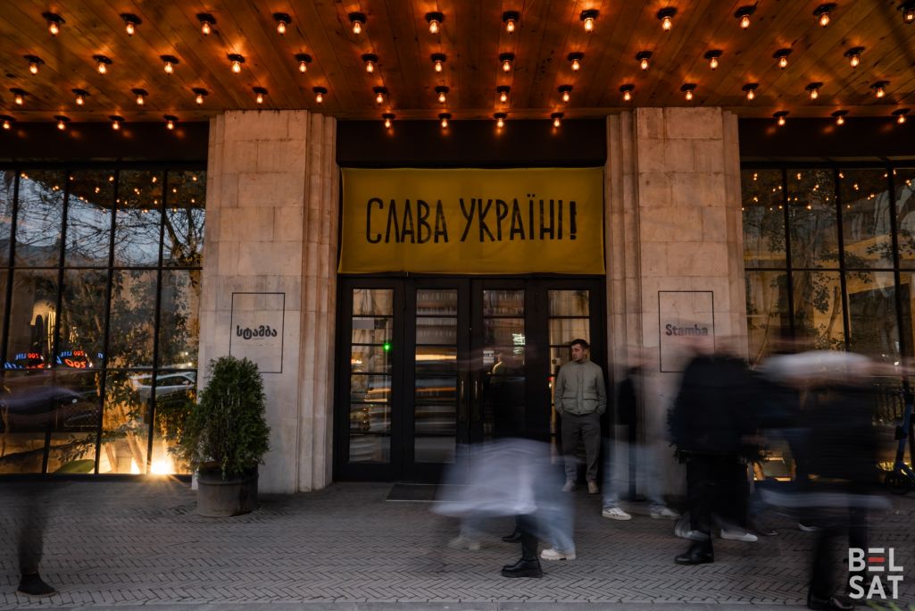 Здымак мае ілюстрацыйны характар. Людзі спяшаюцца дадому з працы на фоне прасторы Stamba, дзе вісіць транспарант з надпісам «Слава Украіне!». Тбілісі, Грузія. 25 лютага 2024 года. (Фота: Белсат)