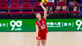 Polska siatkarka Julia Nowicka w czerwonym stroju z numerem 62 wykonuje serwis podczas meczu, w tle puste czerwone krzesła i zielony baner reklamowy. Zdjęcie związane z jej transferem z BKS BOSTIK Bielsko-Biała do brazylijskiego klubu Gerdau/Minas, gdzie zadebiutowała jako MVP pierwszego meczu sezonu. (fot. Getty Images)