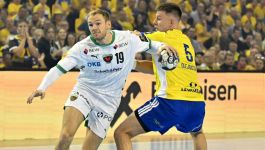 Mathias Gidsel rzucił 13 goli i poprowadził Fuechse Berlin do zwycięstwa nad Industrią Kielce (fot. PAP / Piotr Polak) Zawodnik Füchse Berlin w białym stroju z numerem 19 próbuje przedostać się przez obronę zawodnika Industrii Kielce, ubranego w żółto-niebieski strój z numerem 5 i nazwiskiem "Olejniczak". Akcja ma miejsce podczas meczu 3. kolejki Ligi Mistrzów piłkarzy ręcznych, w którym niemiecki zespół dominował, wygrywając 37:32. W tle widoczna żółta ściana kibiców dopingujących gospodarzy. Mimo ambitnej walki kielczan, to berlińczycy — prowadzeni przez Groendahla, Gidsela i Milosavljeva — kontrolowali przebieg spotkania