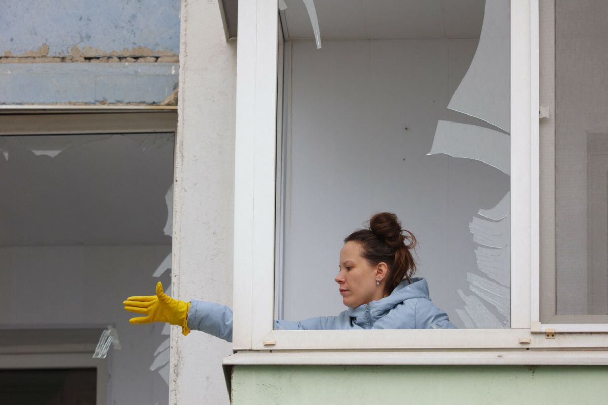 Здымак мае ілюстрацыйны характар. Жанчына дастае аскепкі шкла з гаўбца ў пашкоджаным жылым доме ў Белгарадзе, Расея. 22 сакавіка 2024 года. (Фота: Stringer / AFP / East News)