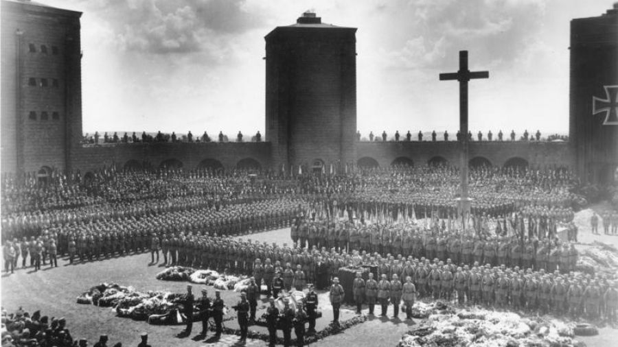 7 sierpnia 1934 r.  Tannenberg Memorial ((oficjalnie  Narodowy Pomnik Tannenberg), pogrzeb Generalfeldmarschalla Paula von Hindenburga, dowódcy niemieckiej armii podczas I wojny światowej i ostatniego prezydenta Niemiec, od 1925 roku aż do śmierci, który mianował Adolfa Hitlera na kanclerza Rzeszy. Furer wygłasza przemówienie na ambonie przed trumną. Fot. Bundesarchiv, Bild 183-2006-0429-502 / CC-BY-SA 3.0, CC BY-SA 3.0 de, https://commons.wikimedia.org/w/index.php?curid=5348669