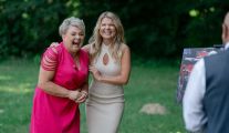 Kadr z programu „Rolnik szuka żony”. Marta Manowska, prowadząca program, obejmuje uczestniczkę Agatę. Agata ubrana jest w różową sukienkę i szeroko się uśmiecha. Marta ma na sobie beżową, dzianinową sukienkę.