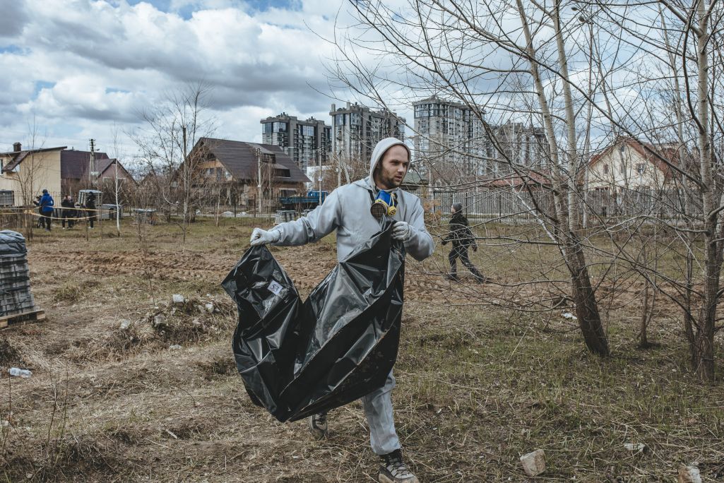 Удзельнік пошукавай групы нясе эксгумаванае цела. Буча, Кіеўская вобласць, Украіна. 12 красавіка 2022 года. (Фота: Белсат)