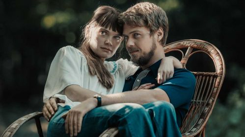 Kadr z filmu „Simona Kossak” przedstawia Sandrę Drzymalską (odtwórczynię tytułowej roli) i Jakuba Gierszała (wcielającego się w Lecha Wilczka). Kobieta siedzi na kolanach mężczyzny i oboje pozują do zdjęcia dla prasy. Film „Simona Kossak” będzie można oglądać odpłatnie od 1 września w TVP VOD.