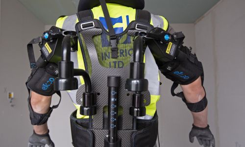 Egzoszkielet może pomagać mięśniom ludzi zdrowych np. dźwigać ciężary. Na zdjęciu pracownik demonstruje Ekso Bionics Inc. EksoVest na budowie osiedla Willmott Dixon Ltd. w Ashton Rise, niedaleko Bristolu w Wielkiej Brytanii, 2019 r. EksoVest kosztowało ok. 7 tys. dolarów, a zapewnia pomoc w dźwiganiu do 7 kg na każde ramię, potencjalnie zmniejszając zmęczenie i obrażenia pracowników. Fot.  Luke MacGregor / Bloomberg przez Getty Images