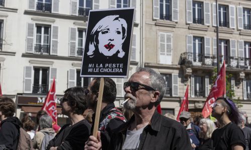 Jeden z 30 ogólnokrajowych protestów przed drugą turą wyborów prezydenckich we Francji, przeciwko kandydującej w nich Marine Le Pen. Zwołała je Liga Praw Człowieka oraz kilku związków zawodowych i studenckich. Protestujący trzyma transparent nazywający ją zarazą (cholerą) i z narysowaną na ustach swastyką, 16 kwietnia 2022 r.  Fot. Sam Tarling/Getty Images